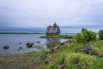 Fototapeta na wymiar Beautiful landscape with a wooden chapel on the shore of Onega bay.