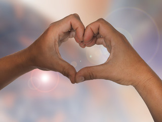 Hände formen ein Herz vor lila Hintergrund