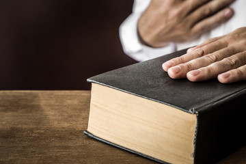 Man's hand swearing on the bible. Taking an oath.  - obrazy, fototapety, plakaty
