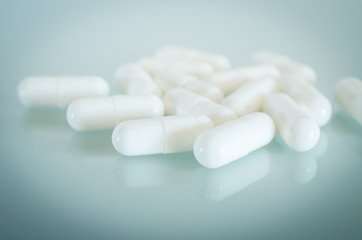 White medical capsules lie on the mirror surface