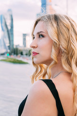 A beautiful young girl is walking along the embankment of Moscow. Dressed in a black dress and denim blue jacket