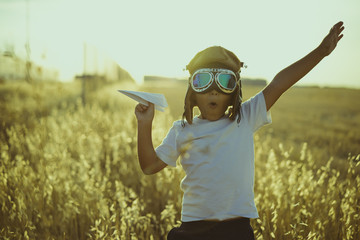 Young Boy playing to be airplane pilot, funny guy with aviator cap and glasses, carries in his hand...