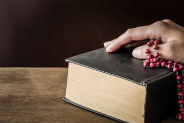 Hand on the bible in the quiet, dark atmosphere. Prayer time on sunday.