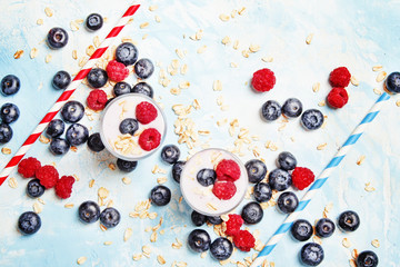 Sweet berry dessert with yogurt, blueberries and raspberries, blue background, top view