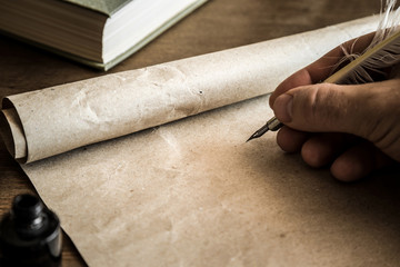 Hand writing with old quill pen on the old paper. Historical atmosphere. Empty place for a text.