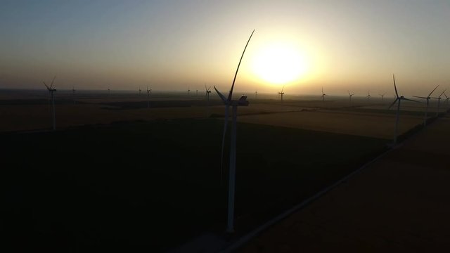 Wind turbines in wheat fields in summer at sunset. Silhouette. Aerial survey