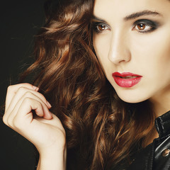 Fototapeta premium Beautiful young woman posing in black leather jacket over grey background. Fashion concept.