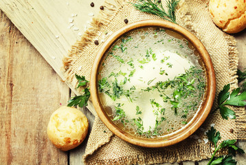 Homemade chicken broth with white meat and buns, vintage wooden background, top view