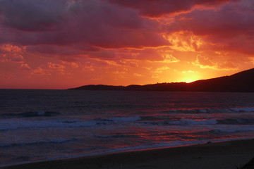 Fototapeta na wymiar Coucher de soleil sur la plage avec un ciel nuageux : rougeur vive