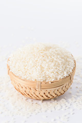 raw rice in a bamboo basket isolated on white background
