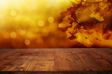 Naklejka na ściany i meble Golden autumn leaves background with wooden table