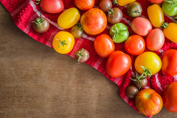 Different tomatoes on the wooden table. Healthy eating and lifestyle. Rustic atmosphere. Harvest background. Food concept. Top view.