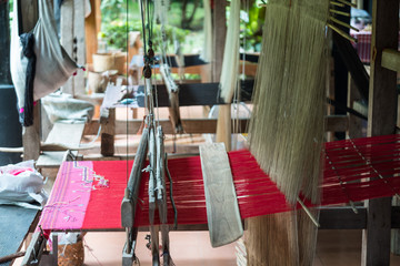 Fototapeta na wymiar Red textile on the handloom for local textile in the North of Thailand.