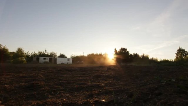 Silhouette shot of a horse rider with dust blowing - sunset, in front of the sun, slow-motion