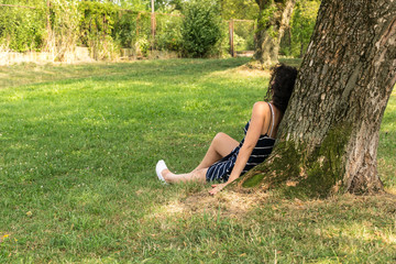 Young woman sitting by the tree in park