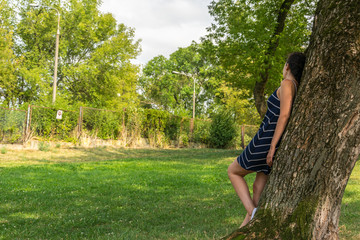 Young woman standing by the tree in park