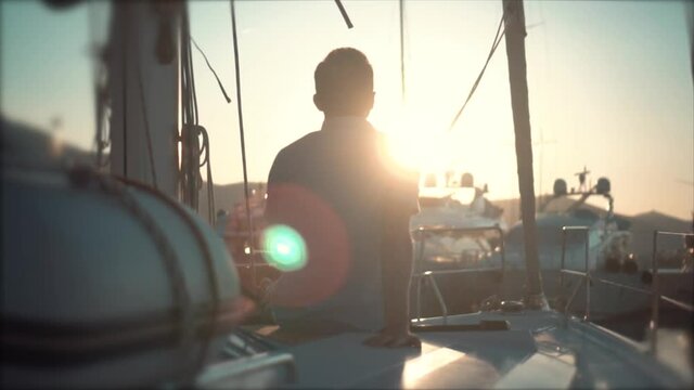 Handsome man looking at the bay with yachts on a sunset.