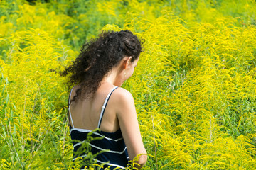 Young woman standing in yellow flowers field