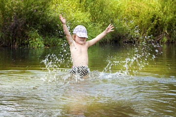 happy kid splashing on summer river