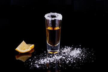Gold Mexican tequila with salt on black background. Alcoholic drink concept. selective focus