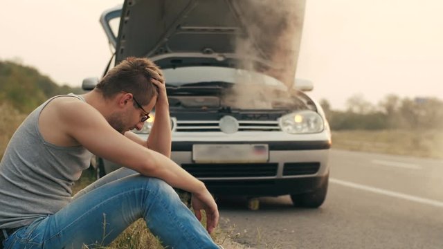 Car with overheated engine and sad man