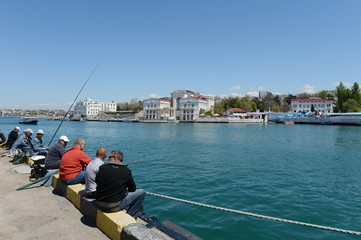 Fototapeta na wymiar Fishermen on the embankment of Sevastopol.