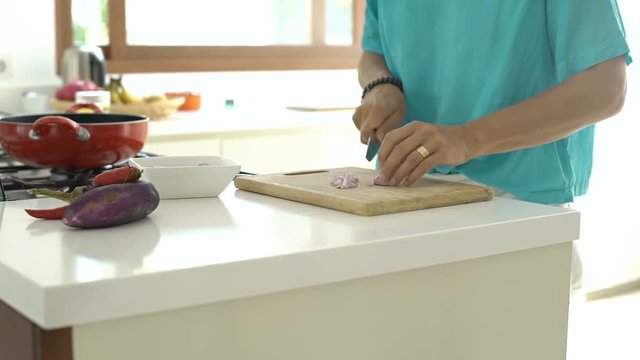 Woman standing in the kitchen and chopping onion on the wooden board, steadycam shot
