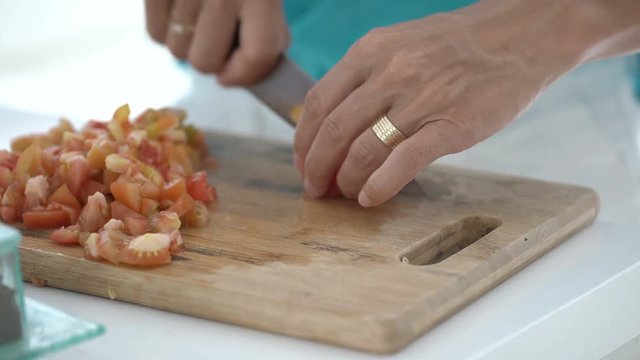 Woman using knife while cutting tomatoes on the chopping board, steadycam shot
