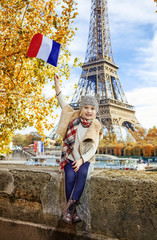elegant child rising flag while sitting on the parapet in Paris