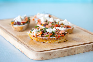 Bruschetta with tomato, cheese and olive oil on a blue background
