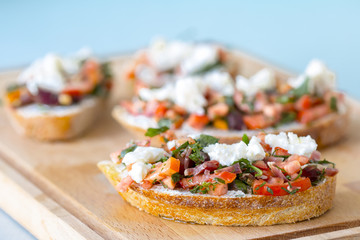 Bruschetta with tomato, cheese and olive oil on a blue background