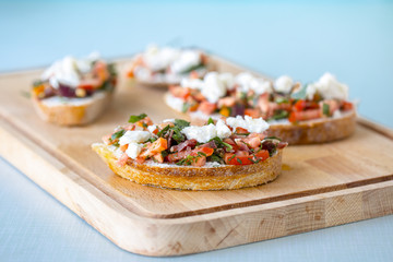 Bruschetta with tomato, cheese and olive oil on a blue background