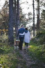 Young couple enjoying nature outdoors together with their adorable Saint Bernard puppy. People and dogs theme.
