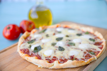 pizza with olive oil and tomatoes on a blue background