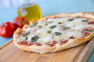 Pizza with olive oil and tomatoes on a blue background. Selective focus