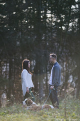 Fototapeta premium Young couple enjoying nature outdoors together with their adorable Saint Bernard puppy. People and dogs theme.