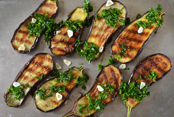 Baked eggplants with pesto and garlic sauce on a metal, grunge background