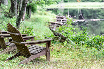 Empty Adirondack chairs along wooded shoreline