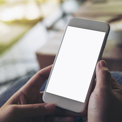 Mockup image of hands holding white mobile phone with blank screen with blur wooden table background in cafe
