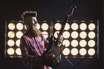 Young punk rocker man playing electric guitar. Excited man on a stage