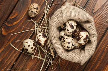 top view on quail eggs in burlap sack over old wooden background