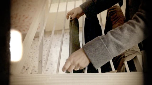 Fake 8mm amateur film: a woman arranging clean clothes on a dryer. Side shot.
