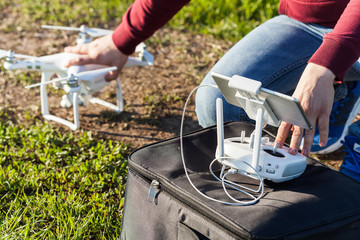 quadcopter flights outdoors, aerial imagery and tech hobby concept - preparing to launch a drone on a summer lawn with green grass, male hands of pilot holding the quadrocopter and remote control
