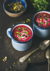 Spring detox beetroot soup with mint, pistachio, chia, flax, pumpkin seeds in blue enamel mugs over dark wooden background. Clean eating, healthy, vegetarian, vegan, dieting, weight loss concept