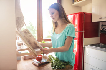 Girl reading a cookbook and preparing some food
