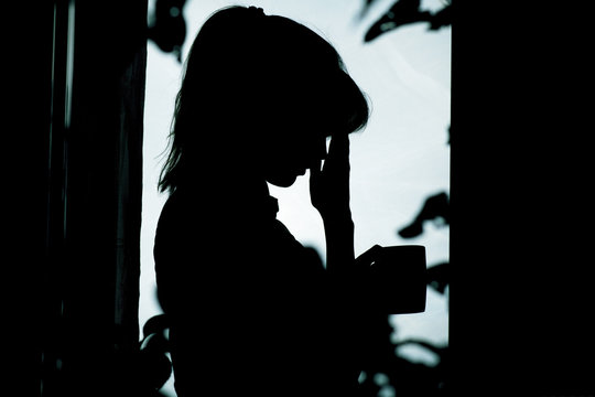 woman silhouette in depression, sad girl standing near window and drinking tea