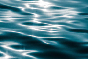 Water surface with moving wave of blue water reflecting light
