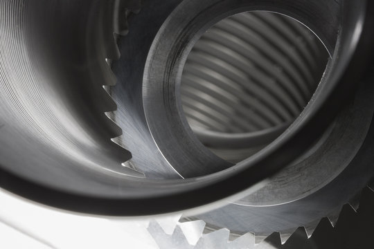 Carbide saw in a steel wire coil lit from beneath. Both used in making parts for automotive industry. 