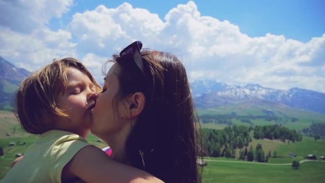 Mother walking holding little girl kissing in love medium shot