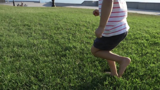An adorable little girl running on the grass at city park